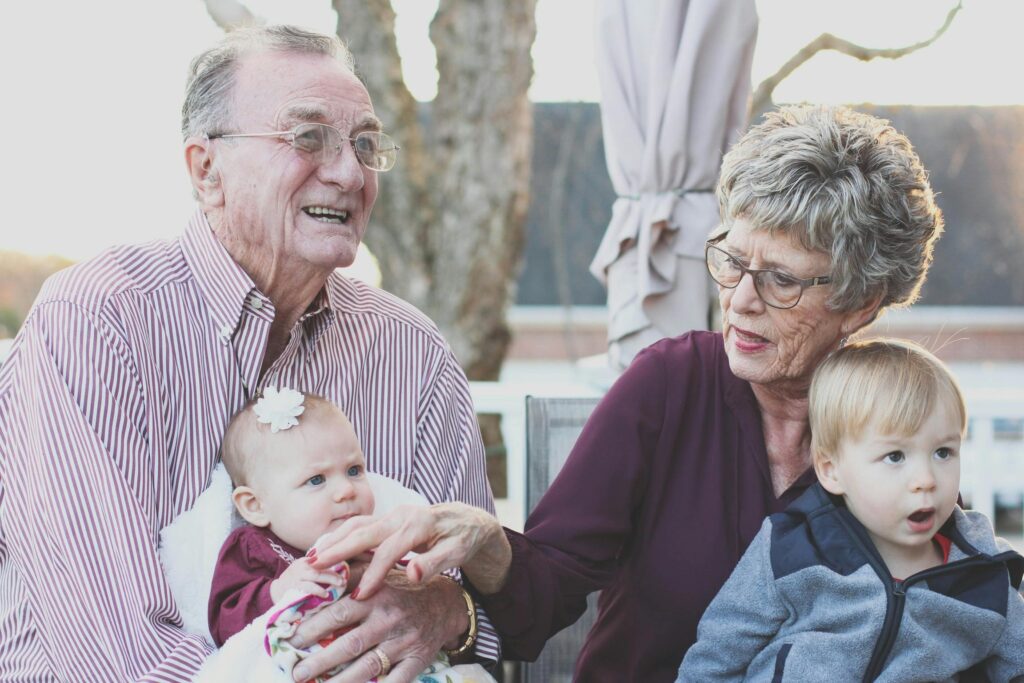 pexels-photo-302083-302083 Grandmother and Grandfather Holding Child on Their Lap
